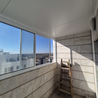 מרפסת עם חלונות אלומיניום וסולם עץ בפינה