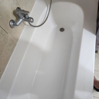 אמבטיה לבנה עם ברז מתכת וצינור גמיש