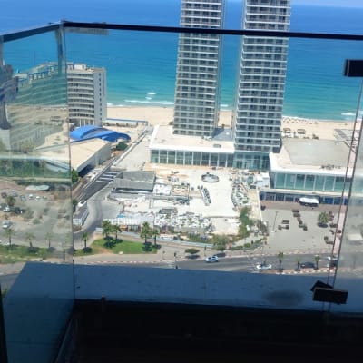 מעקה זכוכית עם נוף לים ולבניינים