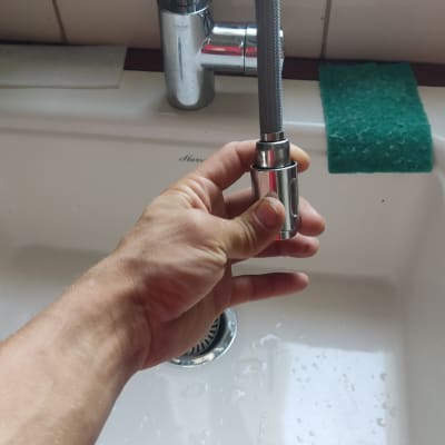 יד מחזיקה צינור ברז נשלף בכיור מטבח