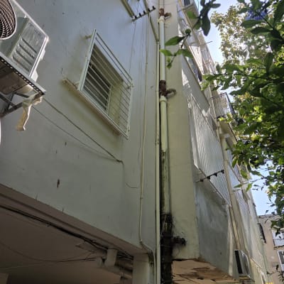 צנרת חיצונית על קיר בניין עם מזגנים