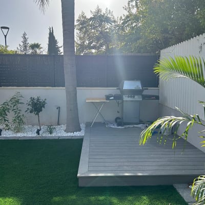 גריל גז על דק עץ בגינה עם דשא סינתטי