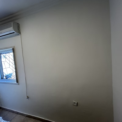 קיר צבוע בלבן עם מזגן וחלון קטן