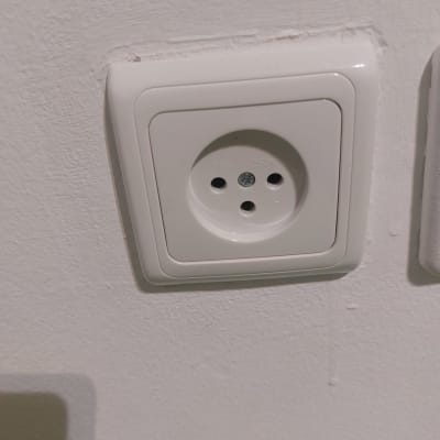 שקע חשמל לבן עם שלושה חורים בקיר