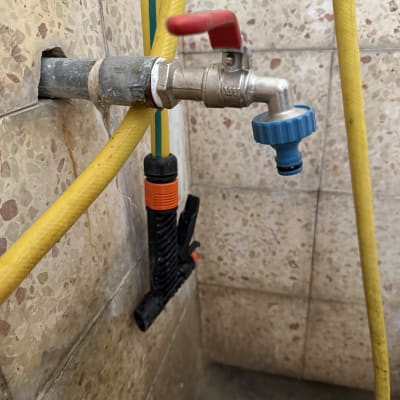 ברז מתכת עם ידית אדומה וצינור צהוב