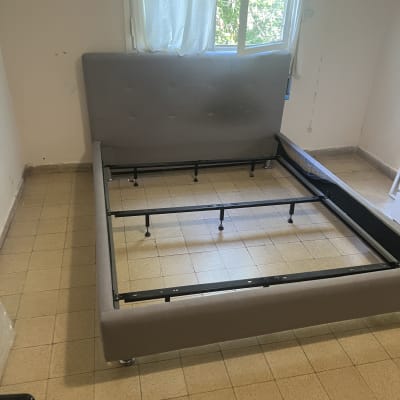 מיטה מפורקת בחדר ריק עם חלון פתוח