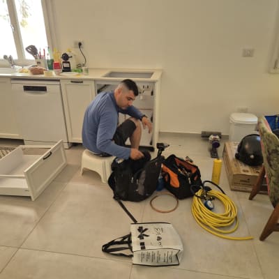 אדם עובד עם כלים ליד ארון מטבח פתוח