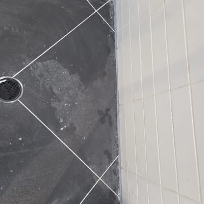 ריצוף חדש במקלחת עם אריחים כהים וניקוז