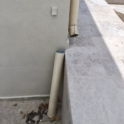 צינור ניקוז ליד קיר חיצוני עם עלים יבשים