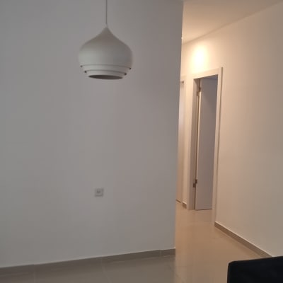 קיר לבן עם מנורה תלויה ודלת פתוחה