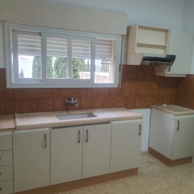 מטבח עם ארונות לבנים וכיור מתחת לחלון