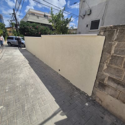 קיר חדש צבוע בצבע בהיר לצד שביל מרוצף