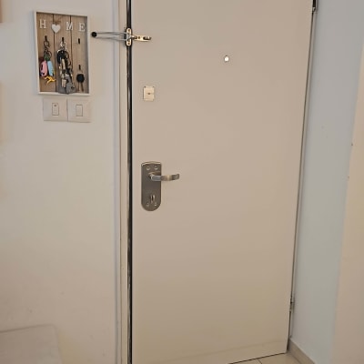 דלת לבנה עם ידית מתכת ובריח עליון