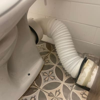 אסלה וצינור חיבור לבן על רצפה מעוצבת