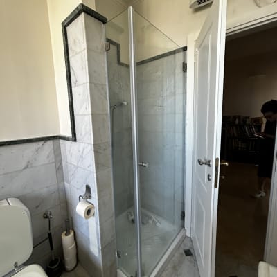 מקלחון זכוכית עם בקבוקי שמפו על הרצפה