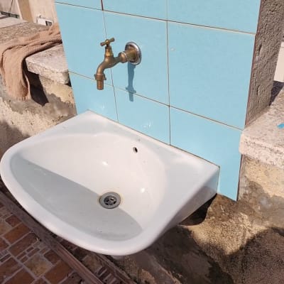 כיור חיצוני עם ברז על קיר מרוצף באריחים כחולים