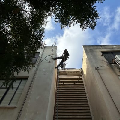 אדם עובד על סולם גבוה בין שני בניינים