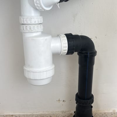 צנרת פלסטיק לבנה ושחורה מתחת לכיור