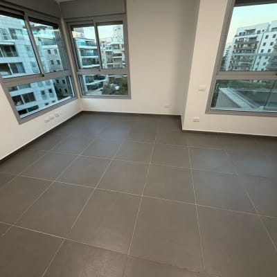 חדר ריק עם רצפת אריחים וחלונות גדולים
