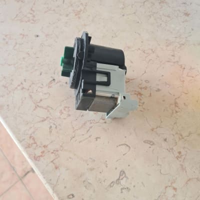 רכיב חשמלי עם חיבורים ירוקים ושחורים על משטח שיש