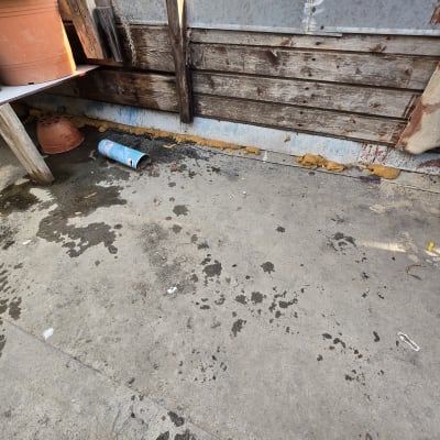 כתמי רטיבות על רצפה ליד קיר עץ ומתכת