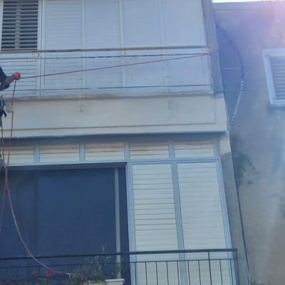 אדם עם קסדה עובד על איטום קיר חיצוני