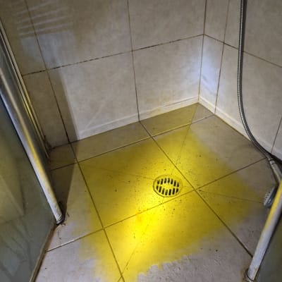 רצפת מקלחת עם כתם צהוב סביב הניקוז