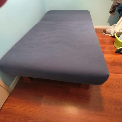 מיטה עם מזרן כחול בחדר עם רצפת עץ