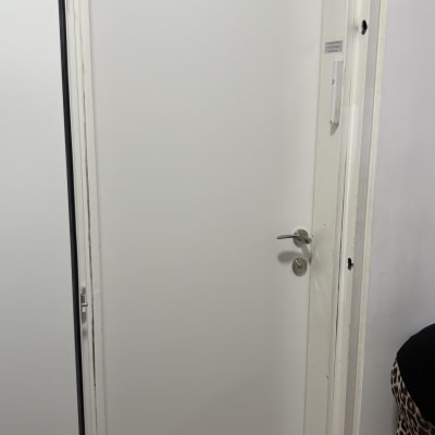 דלת לבנה עם ידית כסופה מותקנת במסגרת קיר