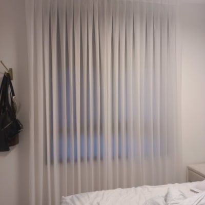 וילון לבן תלוי בחדר שינה עם מיטה