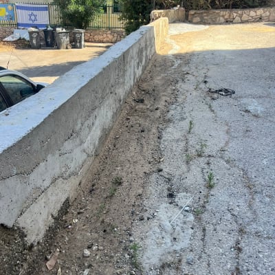 קיר בטון וחניה עם צמחייה מסביב