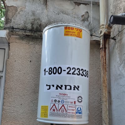דוד שמש מותקן על קיר חיצוני עם מספר טלפון