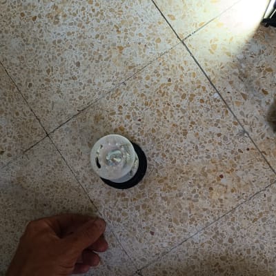 יד מחזיקה חלק פלסטיק עגול על רצפה