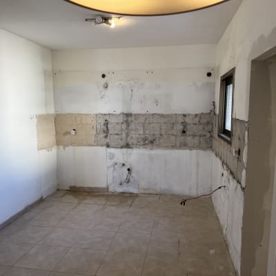 חדר בשיפוץ עם קירות חשופים ורצפת אריחים