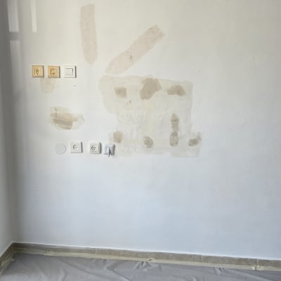 קיר עם תיקוני טיח ויריעות מגן על הרצפה