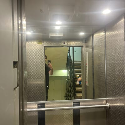 מראה במעלית עם אדם מחזיק חומר ניקוי