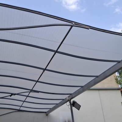 סוכך מותקן על קיר חיצוני עם צמחייה ברקע