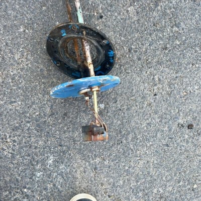 חלק מתכת חלוד על הקרקע ליד נעליים