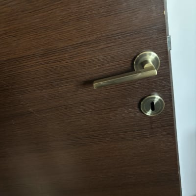 ידית דלת מתכתית על דלת עץ כהה