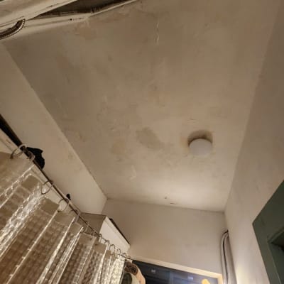 תקרה עם סימני רטיבות ותאורה בחדר אמבטיה