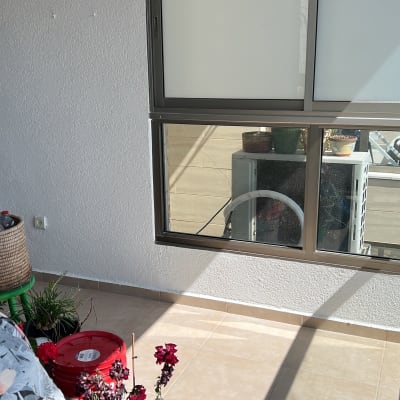 מרפסת עם דלי צבע אדום ומברשת צביעה ירוקה