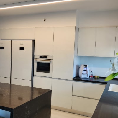 מטבח מודרני עם ארונות לבנים ומכשירי חשמל