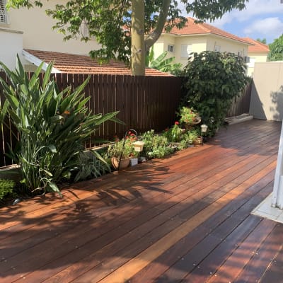 דק עץ עם צמחים ופרחים בגינה קטנה