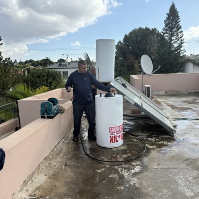 אדם עובד על דוד שמש על גג עם כלים