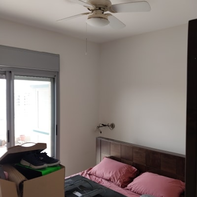 חדר שינה עם מאוורר תקרה ומיטה עם מצעים ורודים