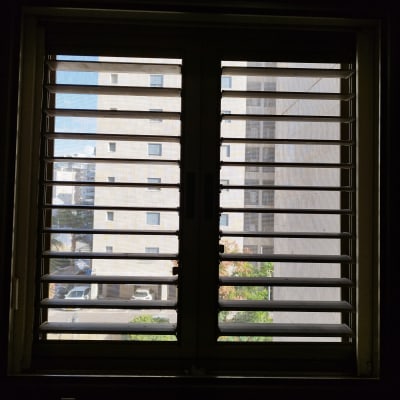 תריסים אופקיים פתוחים על חלון עם נוף עירוני