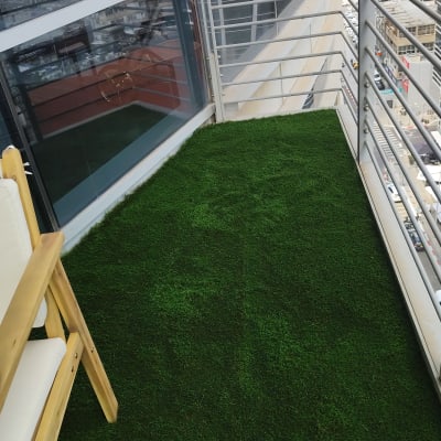 מרפסת עם דשא סינתטי וכיסא עץ