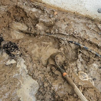 כלים וחפירה באדמה רטובה ליד קיר