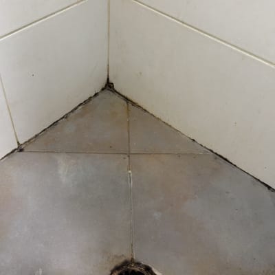 פינת חדר עם אריחי קרמיקה ורצפה מלוכלכת