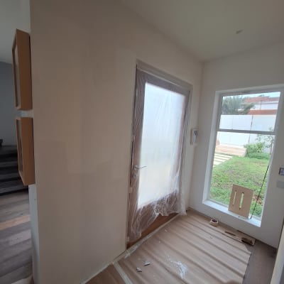 חדר עם דלת מכוסה בניילון, קירות צבועים וכלי צביעה על הרצפה